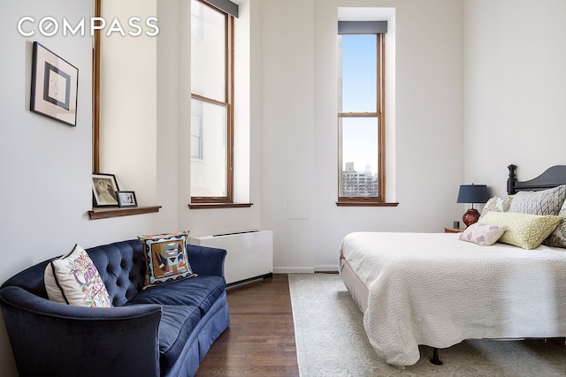 bedroom with dark wood-style floors, radiator heating unit, and baseboards