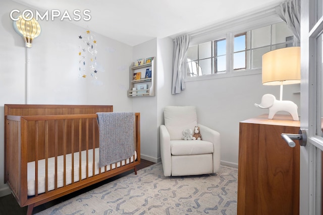 bedroom featuring a nursery area and baseboards