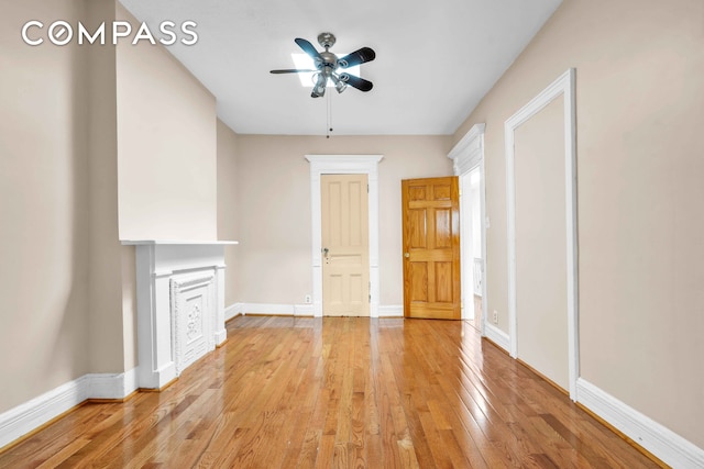 unfurnished living room featuring ceiling fan, light wood-style flooring, and baseboards