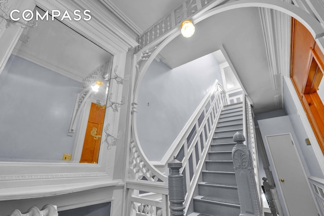 stairway featuring arched walkways and crown molding