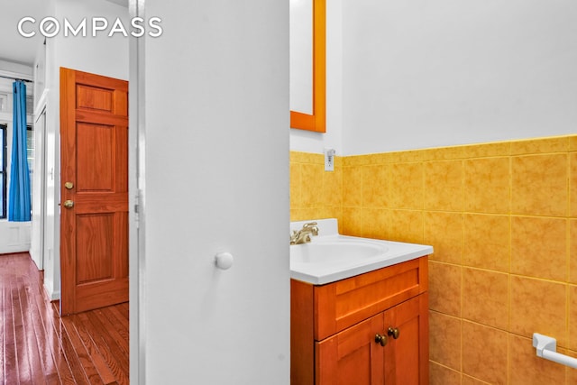 bathroom with tile walls, a wainscoted wall, wood finished floors, and vanity