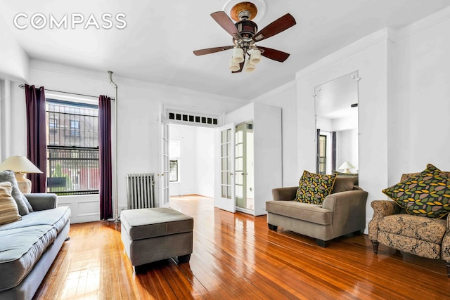 living room with radiator heating unit, ceiling fan, hardwood / wood-style floors, and french doors