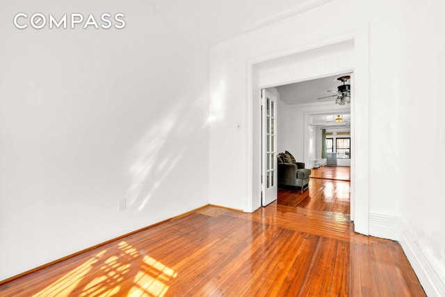 unfurnished room with baseboards, a ceiling fan, hardwood / wood-style flooring, and ornamental molding