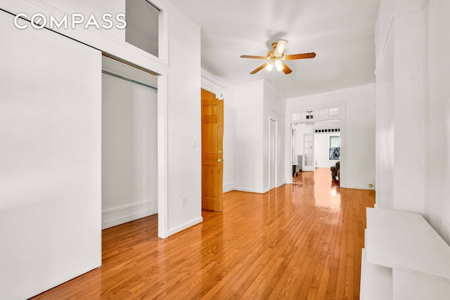 interior space with light wood-type flooring, a ceiling fan, and baseboards