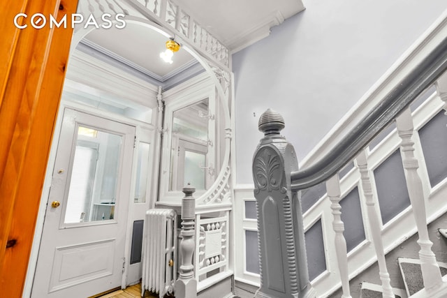 interior space featuring crown molding, a decorative wall, and stairs