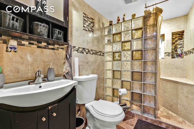 full bathroom with toilet, walk in shower, tile walls, and vanity