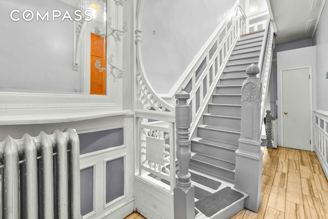 stairs featuring radiator heating unit and wood finished floors