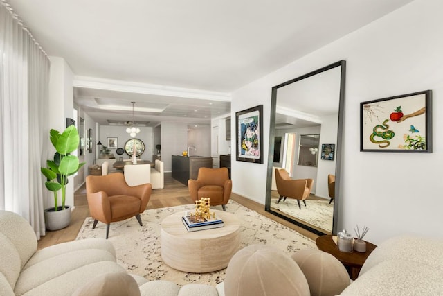 living room with an inviting chandelier, sink, and light hardwood / wood-style flooring