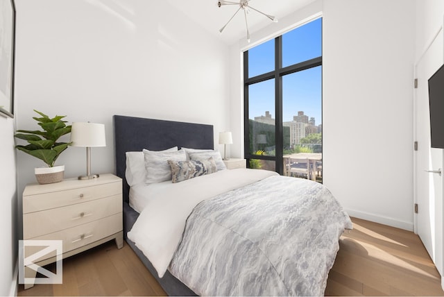 bedroom with lofted ceiling, an inviting chandelier, access to exterior, and light wood finished floors