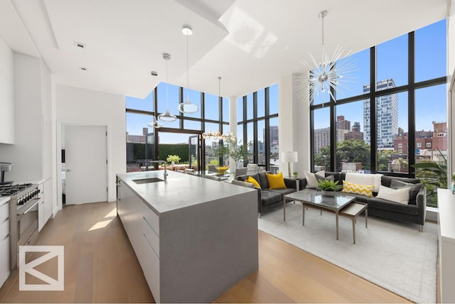 kitchen with a sink, a view of city, a notable chandelier, and stainless steel stove