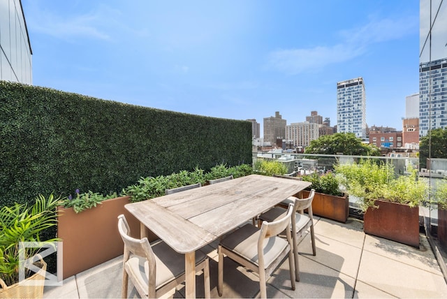 view of patio featuring a view of city, a balcony, and outdoor dining space