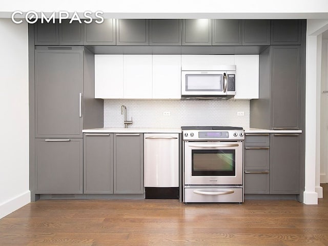 kitchen with stainless steel appliances, gray cabinets, light countertops, and light wood finished floors