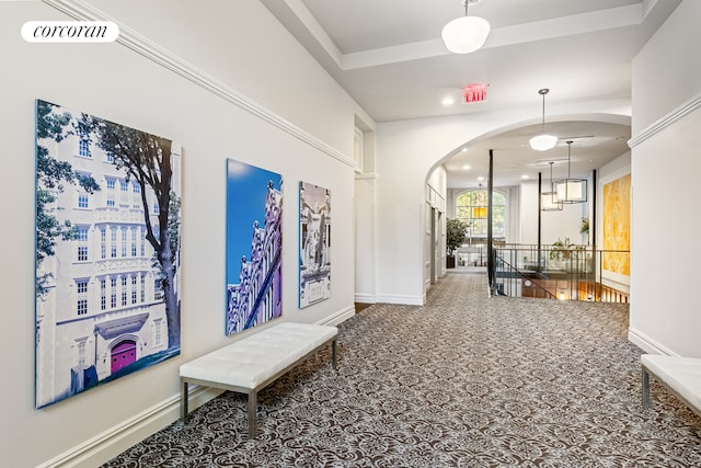 hall featuring arched walkways, carpet floors, baseboards, recessed lighting, and an upstairs landing
