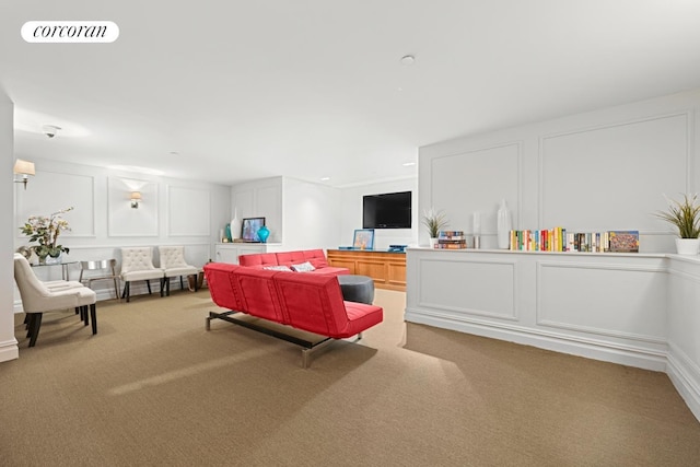 living area featuring carpet and a decorative wall