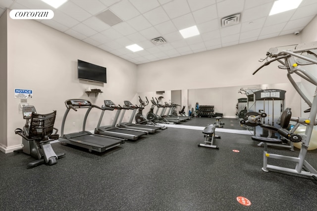 exercise room with a drop ceiling and baseboards