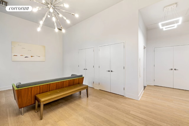 sitting room featuring a towering ceiling, light hardwood / wood-style floors, and a notable chandelier