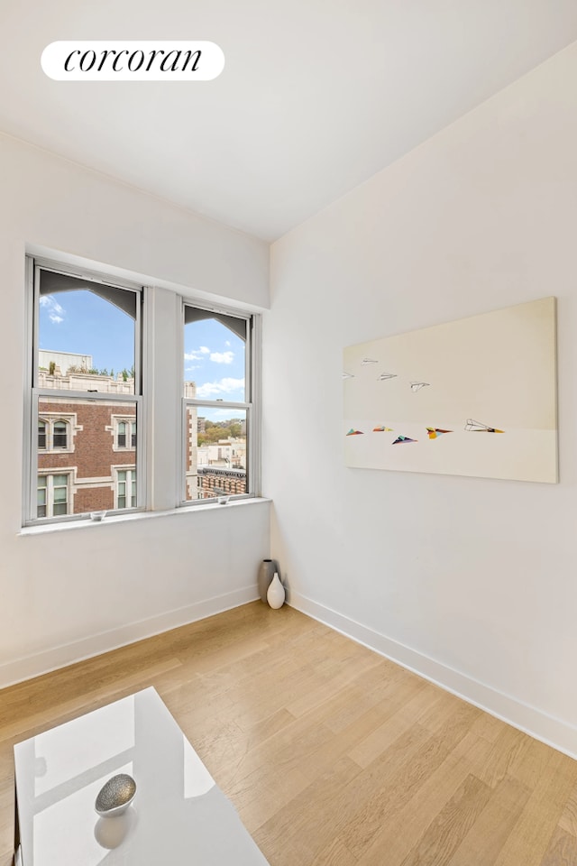empty room with wood finished floors, baseboards, and plenty of natural light