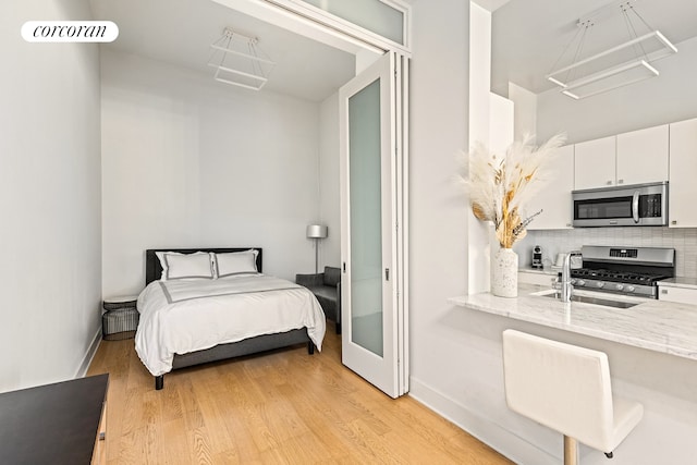 bedroom featuring light wood-style flooring, baseboards, and a sink