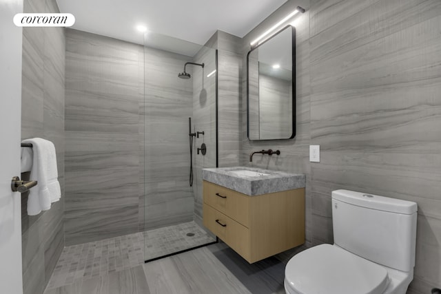 bathroom featuring vanity, a tile shower, and toilet