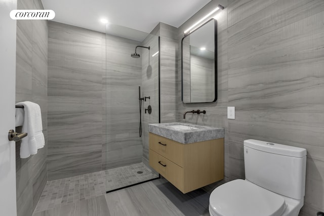 full bathroom featuring tile walls, toilet, walk in shower, and vanity