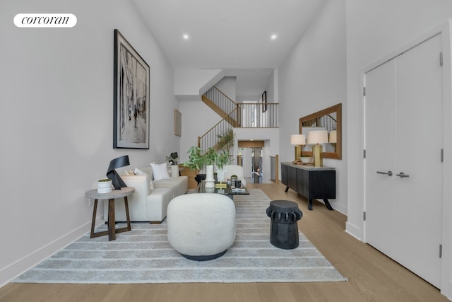 living room featuring stairway, wood finished floors, baseboards, recessed lighting, and a towering ceiling