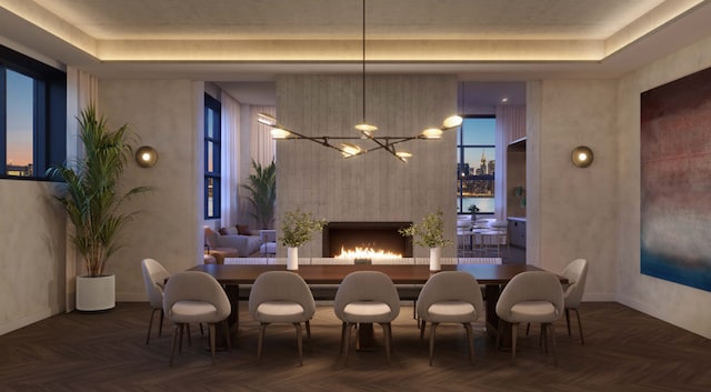 dining area featuring a tray ceiling, a notable chandelier, and dark parquet flooring