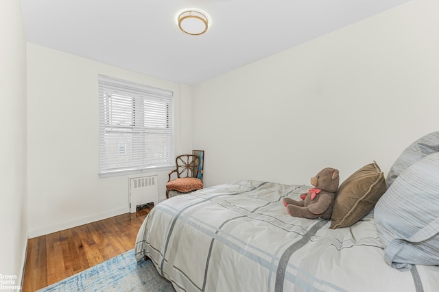 bedroom featuring radiator heating unit, wood finished floors, and baseboards