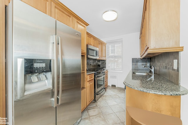 kitchen featuring decorative backsplash, dark stone counters, stainless steel appliances, a sink, and light tile patterned flooring