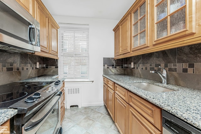 kitchen featuring a sink, appliances with stainless steel finishes, light stone countertops, tasteful backsplash, and radiator heating unit