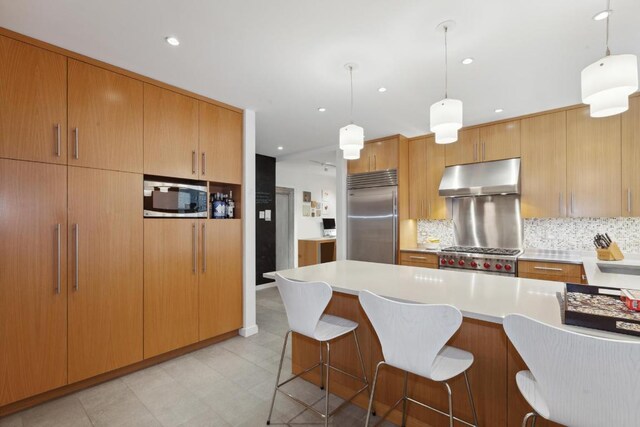 kitchen with decorative light fixtures, a kitchen island, built in appliances, and tasteful backsplash