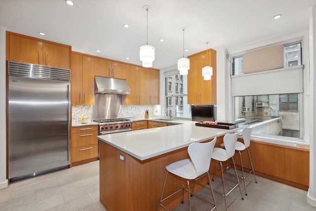 kitchen with pendant lighting, sink, plenty of natural light, a kitchen breakfast bar, and built in refrigerator