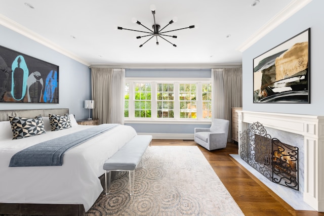 bedroom featuring hardwood / wood-style flooring, ornamental molding, a premium fireplace, and a chandelier