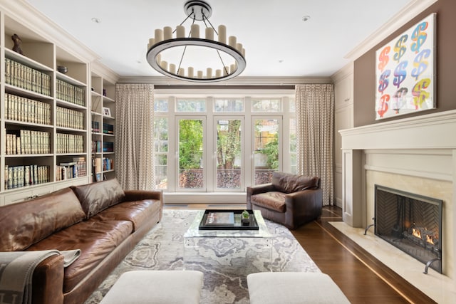 bedroom featuring hardwood / wood-style flooring, ornamental molding, a premium fireplace, and a chandelier