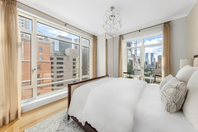 bedroom with wood finished floors, ornamental molding, access to exterior, a city view, and a chandelier