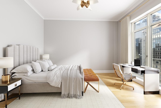 bedroom featuring wood finished floors, a ceiling fan, baseboards, and ornamental molding