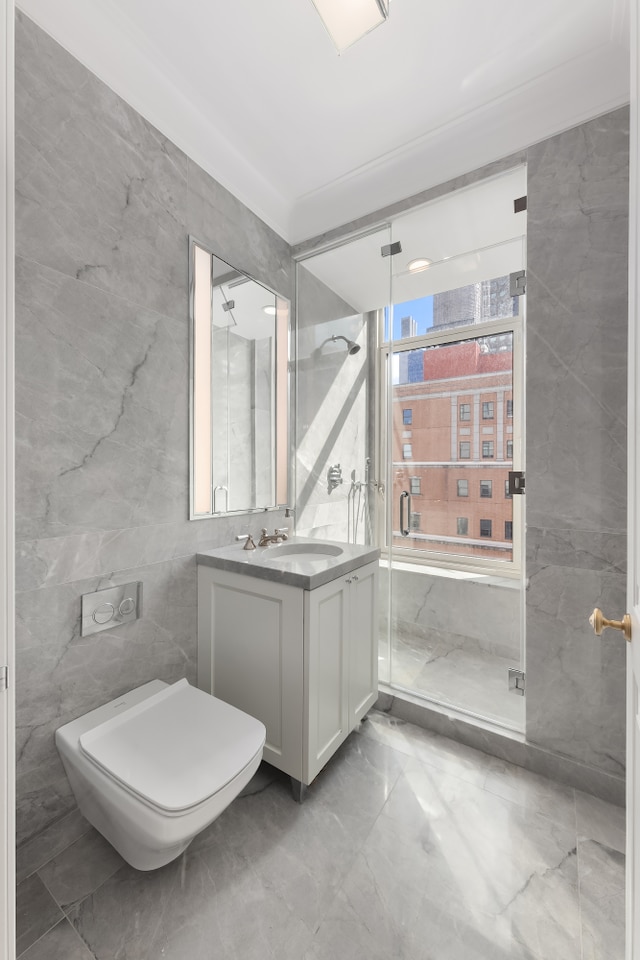 bathroom featuring toilet, marble finish floor, tile walls, a shower stall, and vanity