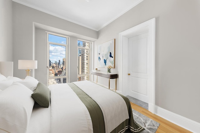 bedroom with crown molding, light wood-type flooring, and baseboards