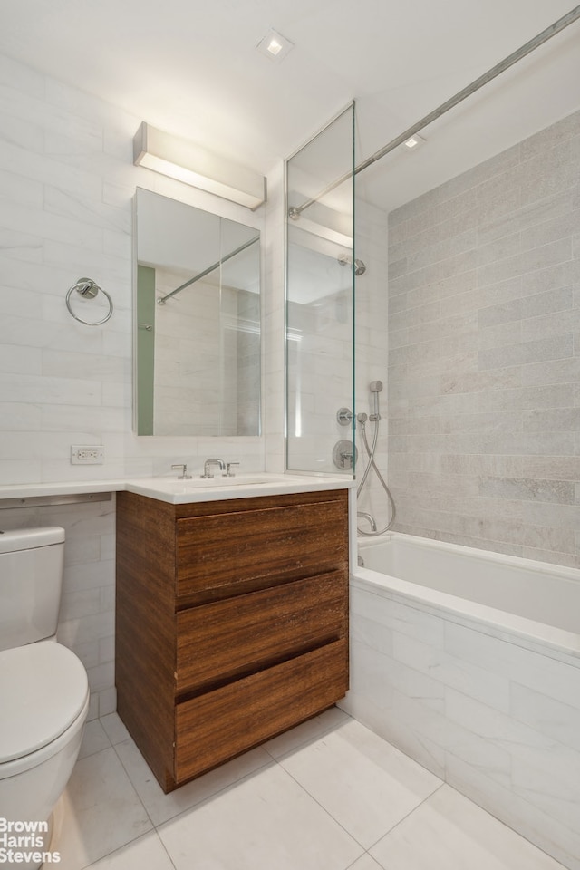 bathroom featuring tiled shower / bath, toilet, tile walls, and vanity