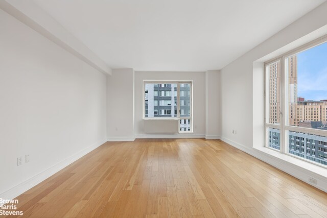 empty room with baseboards and light wood-style floors