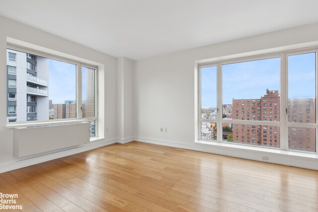 empty room featuring hardwood / wood-style flooring, a view of city, and baseboards