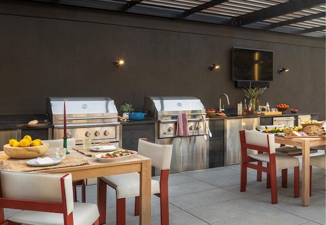 view of patio featuring a sink, an outdoor kitchen, area for grilling, and outdoor dining space