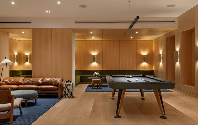 game room with wood walls, billiards, light wood-style flooring, and a barn door