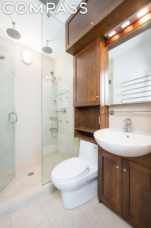 bathroom with toilet, an enclosed shower, vanity, tile patterned flooring, and decorative backsplash