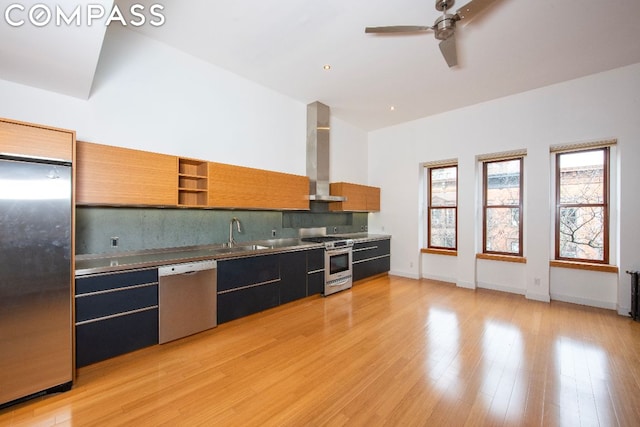 kitchen with appliances with stainless steel finishes, tasteful backsplash, sink, stainless steel counters, and wall chimney range hood