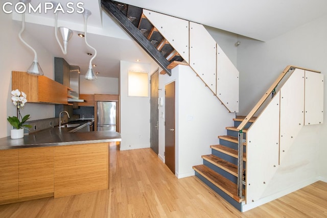 kitchen featuring white cabinetry, sink, light hardwood / wood-style floors, and stainless steel refrigerator