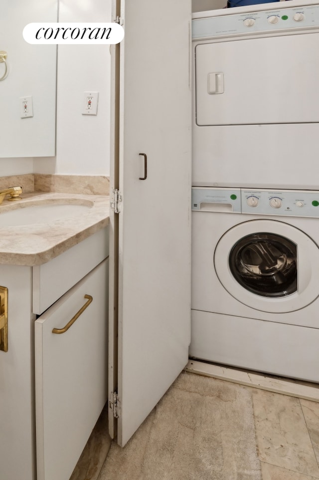 laundry area with stacked washer / drying machine and a sink