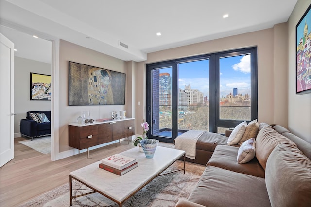 living room with light wood-style flooring, visible vents, recessed lighting, a view of city, and baseboards