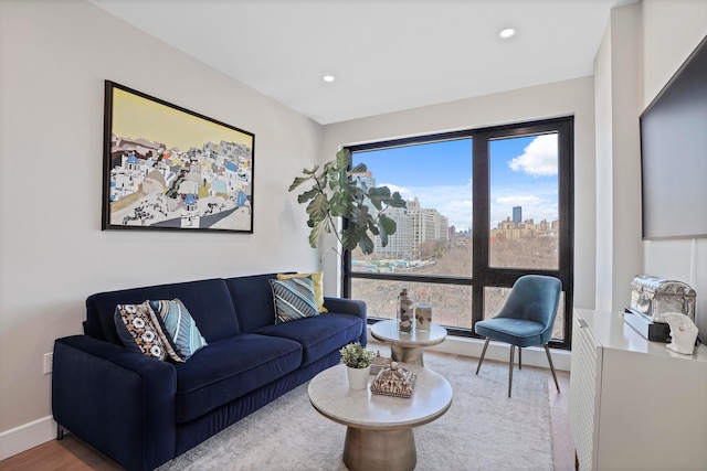 living room featuring recessed lighting, a view of city, baseboards, and wood finished floors