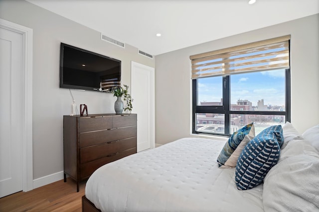 bedroom with recessed lighting, visible vents, baseboards, and wood finished floors