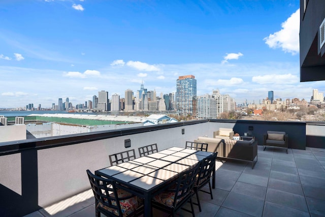 view of patio with a balcony, a city view, and outdoor dining space